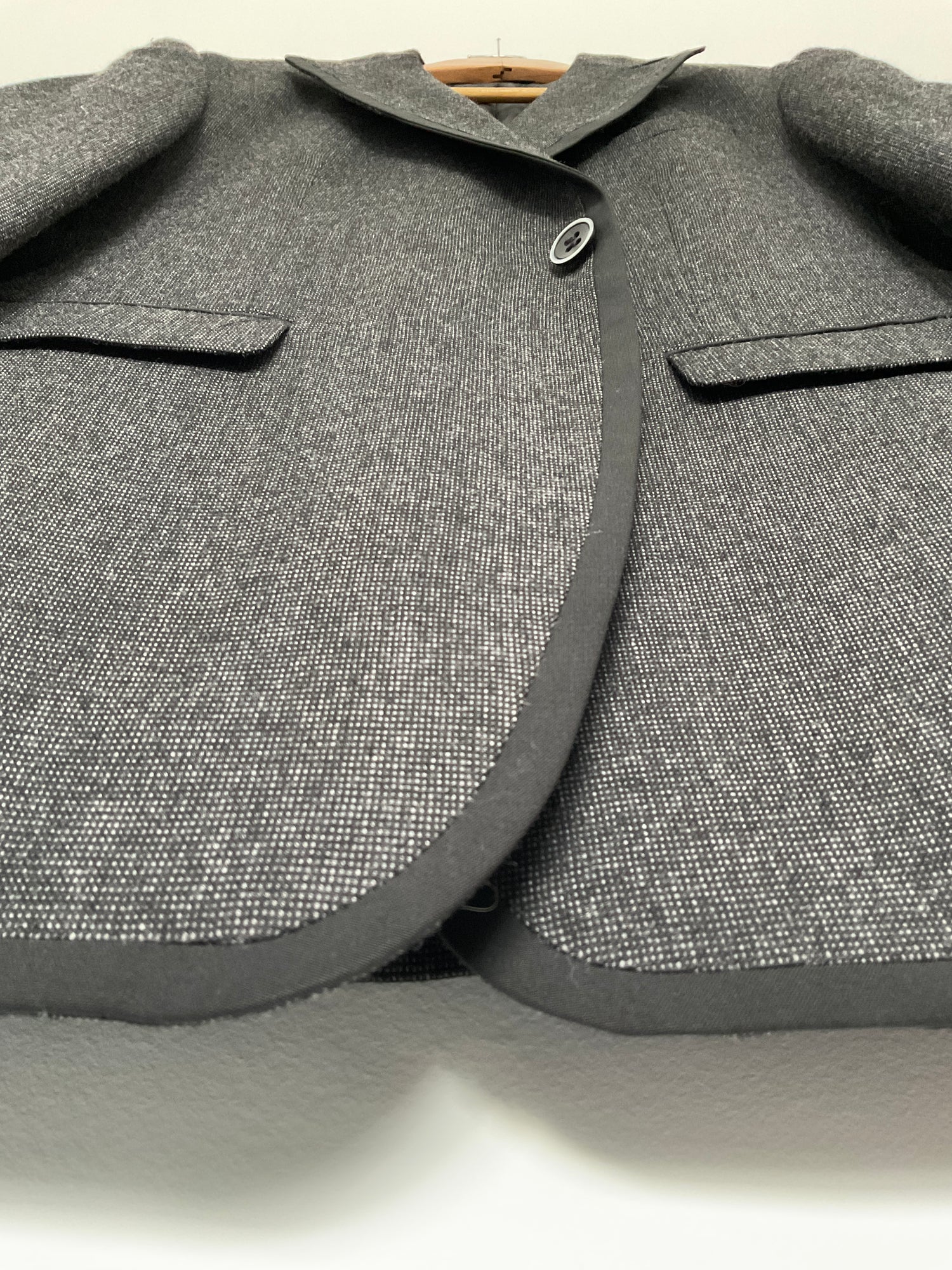 Close-up of a gray textured suit jacket with buttons on a neutral background